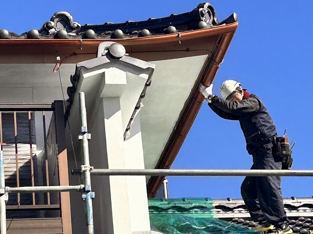 伊那市：屋根の上で雨樋交換工事を行っている職人