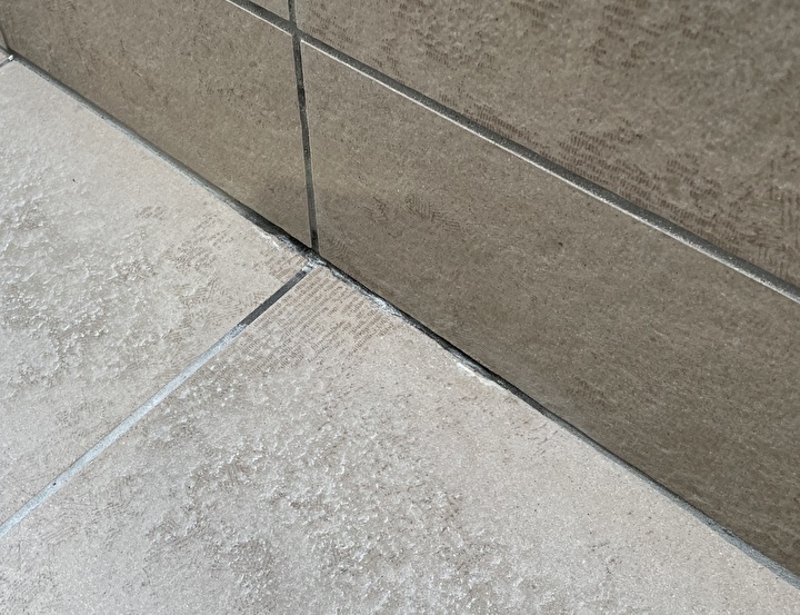 雨染みが確認できる腰壁と床タイルの接合部分