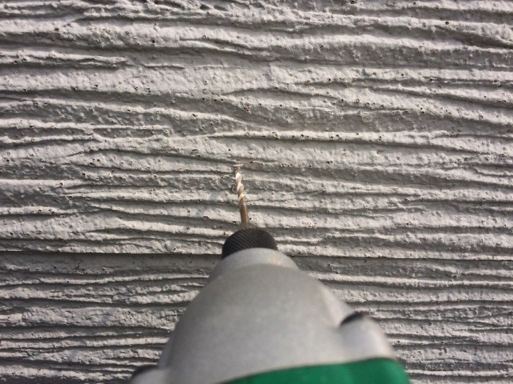 サイディングに細い錐（きり）で下穴を開ける作業