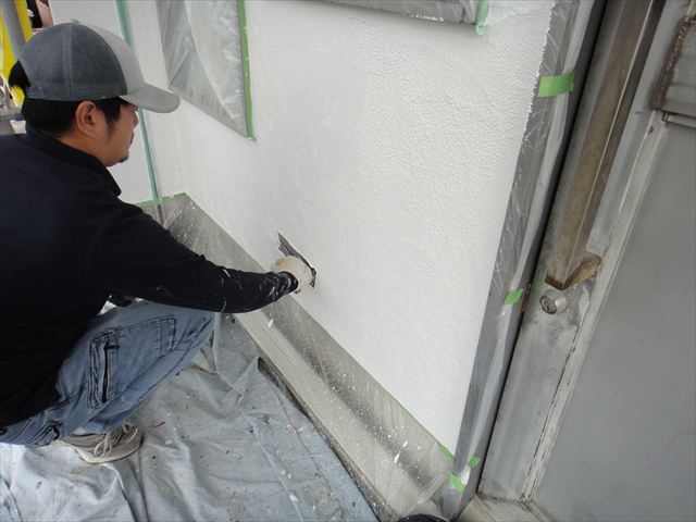 鏝で塗料を抑えている