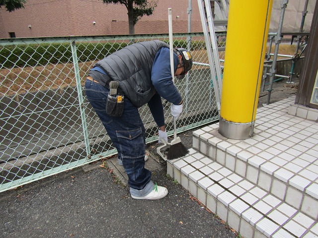 ほうきで履いて掃除する職人さん