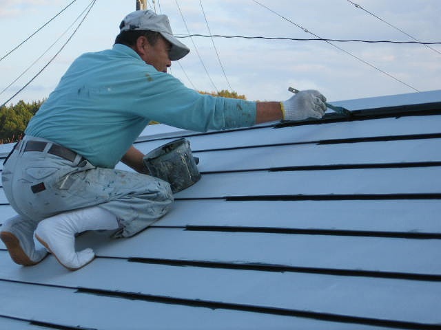 福島市内にあるトタン鋼板の横葺き屋根の狭小部を刷毛で中塗りしています。
