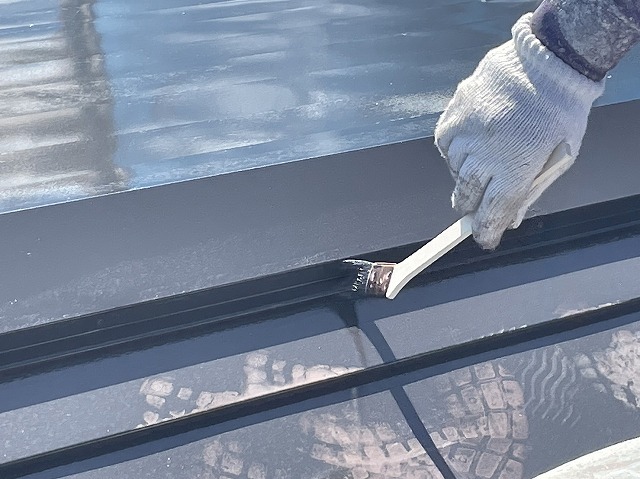 飯田市：ハケを使って金属屋根に塗装をしている状況
