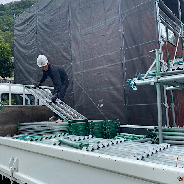 トラックの荷台から足場部材をおろす