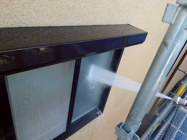 西八代郡市川三郷町でモルタル外壁の塗装前に高圧洗浄を行い、窓ガラスを洗浄する様子