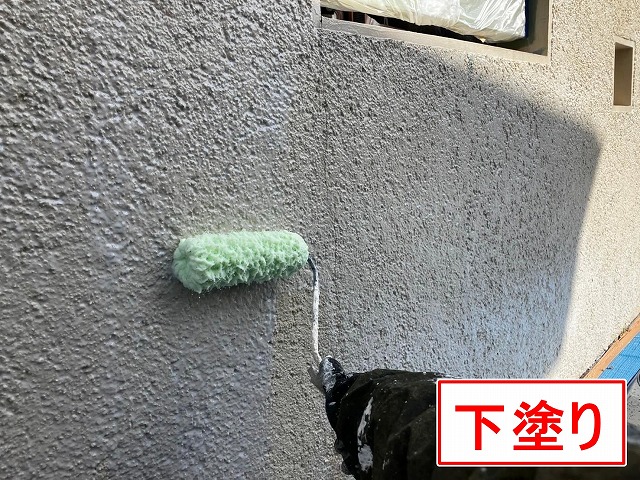 笛吹市でクラック(ひび割れ)の目立つ擁壁に塗装(下塗り)を行う様子