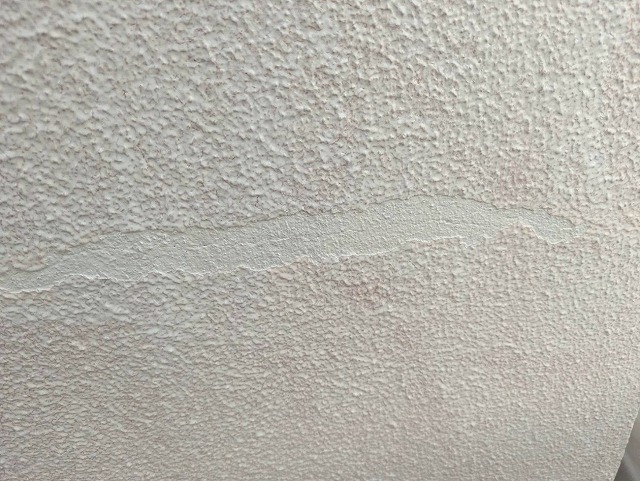 笛吹市でモルタル外壁の塗膜が浮いた箇所を補修する様子