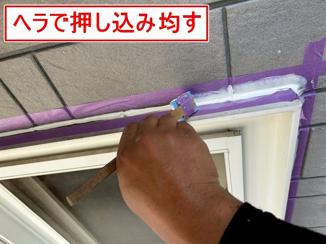 南アルプス市で窓・ドア・換気フードのサッシ廻りにシーリング材を押し込んで均す様子(シーリング増し打ち工事)