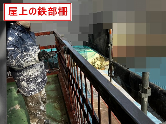 甲府市で塗膜剝がれ・錆びの発生した屋上の鉄部柵にケレン作業後、錆止め塗装(下塗り)を行う様子