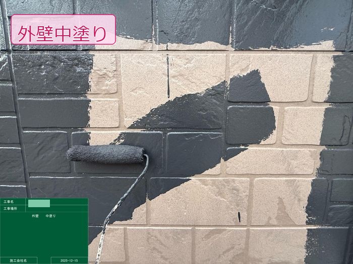 松原市別所のT様邸 外壁サイディングにダークグレーの塗料をローラーで中塗りしている様子