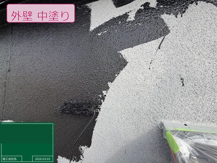 松原市別所のO様邸 モルタル外壁に黒系の中塗り塗料をローラーで大きく広げている施工中の様子