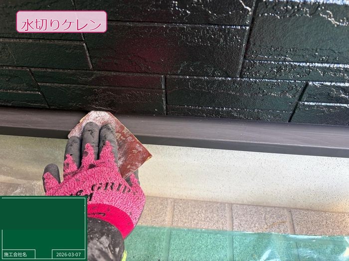 松原市別所のO様邸 水切り(外壁下部の雨水誘導板)のケレン施工中 赤いグローブの職人がやすりで表面を研磨