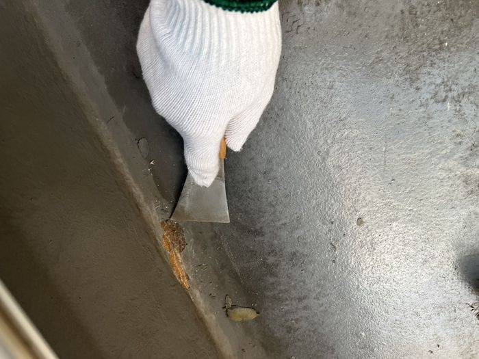 八尾市太子堂のO様邸 スクレーパーでベランダ立ち上がり部の旧塗膜と劣化部を除去している作業