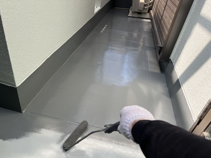 八尾市久宝寺のI様邸 ウレタン防水材2回目の塗布作業 奥から手前へローラーで塗り進めている様子
