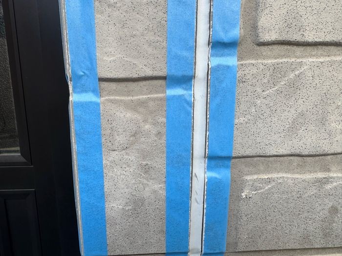 松原市別所のサイディング外壁 玄関扉横の縦目地にマスキングテープと養生紙を丁寧に貼った状態