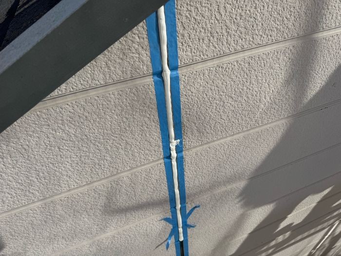 松原市別所のサイディング縦目地にシーリング材をコーキングガンで充填している施工中の様子