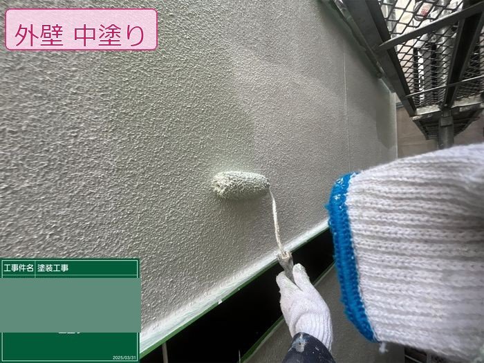八尾市M様邸モルタル外壁の中塗り施工中 ローラーで塗料を均一に塗り広げている様子