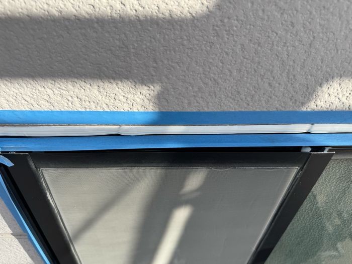 松原市別所のサイディング外壁 窓上の水切り金物に沿ってマスキングテープを直線に貼った養生の様子