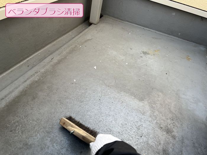 八尾市太子堂のO様邸 防水工事前にブラシでベランダ床面の汚れを掃き出している清掃作業