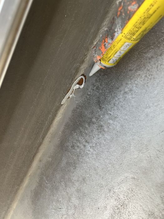 八尾市太子堂のO様邸 ベランダ立ち上がり部の亀裂にコーキングを充填している作業中